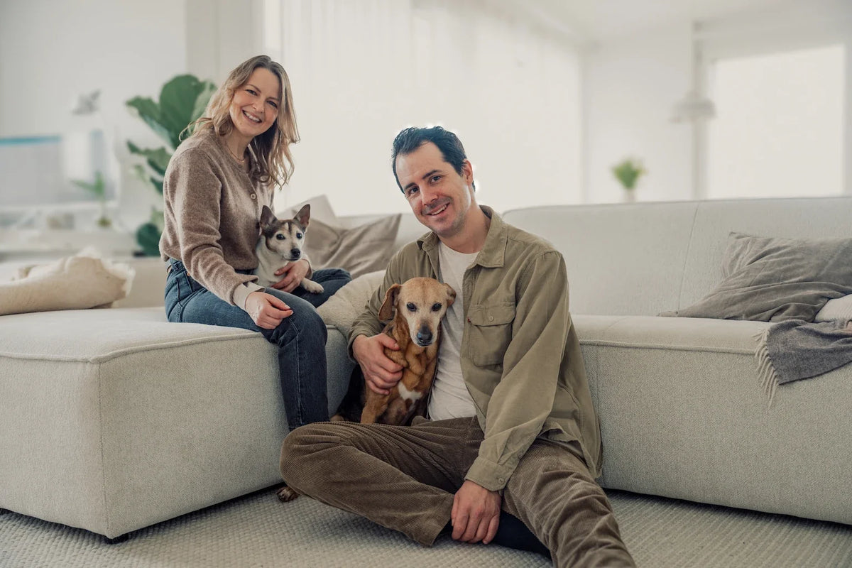 Frau und Mann sitzen mit ihrem Hund auf einem Sofa
